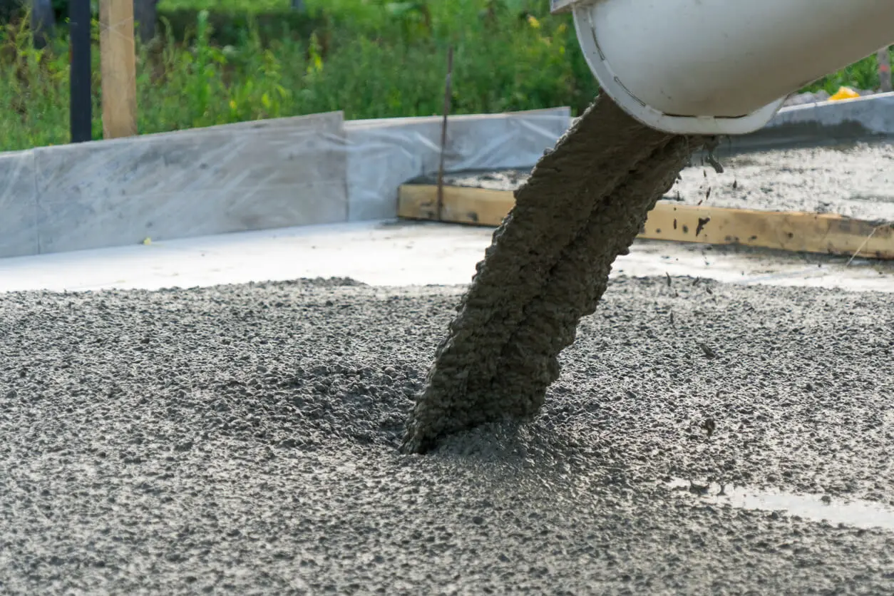 A large tank of ready mix concrete is being poured into the ground.